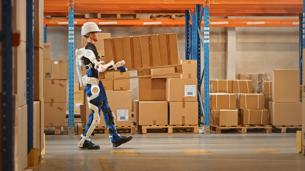 A warehouse worker carrying some boxes using an exoskeleton body suit